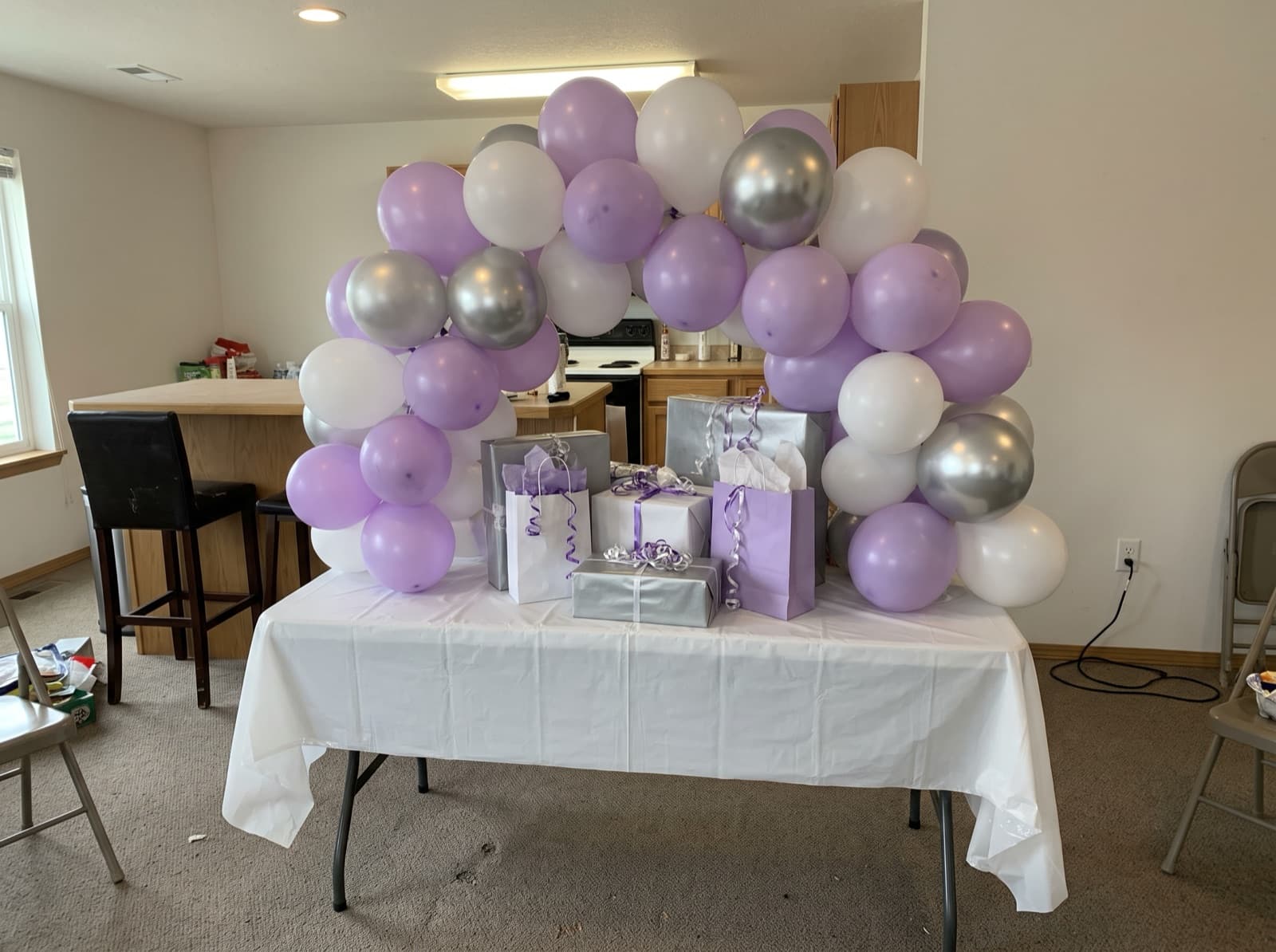 Small lavender and silver tabletop arch over a gift table